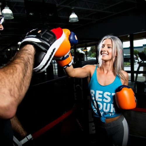 A man and woman enjoy a dynamic boxing workout together in a modern gym setting.